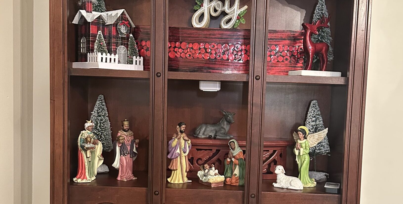 Manger scene display in hutch illuminated by rechargeable puck lights for Christmas