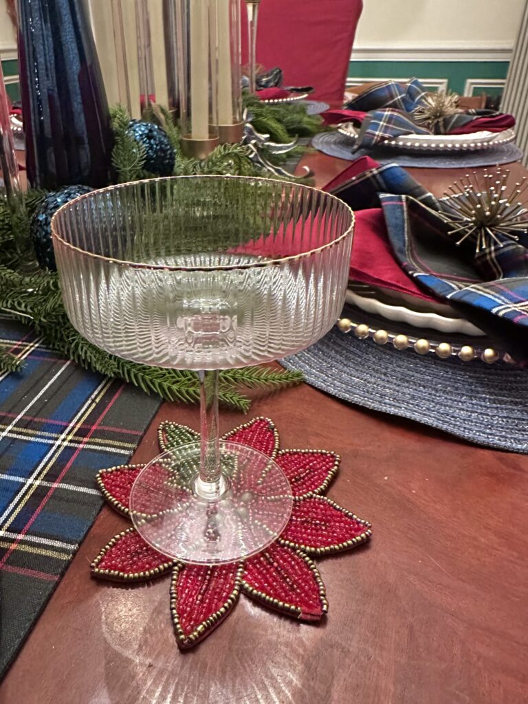 Gold-rimmed coupe glasses placed beside candles and garland on Christmas dining table