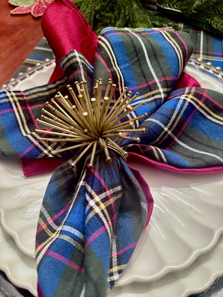 Blue and green tartan plaid napkins with clear acrylic gold charger plates on a Christmas tablescape