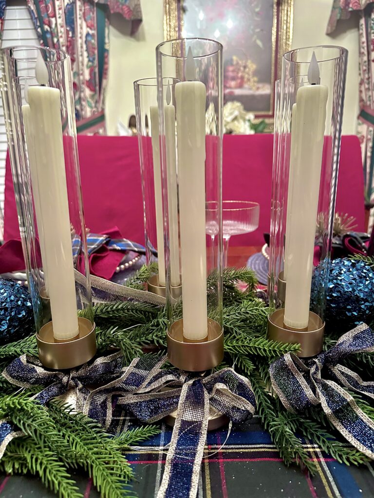 Wax flameless candles inside glass hurricane candle holders on elegant holiday dining table