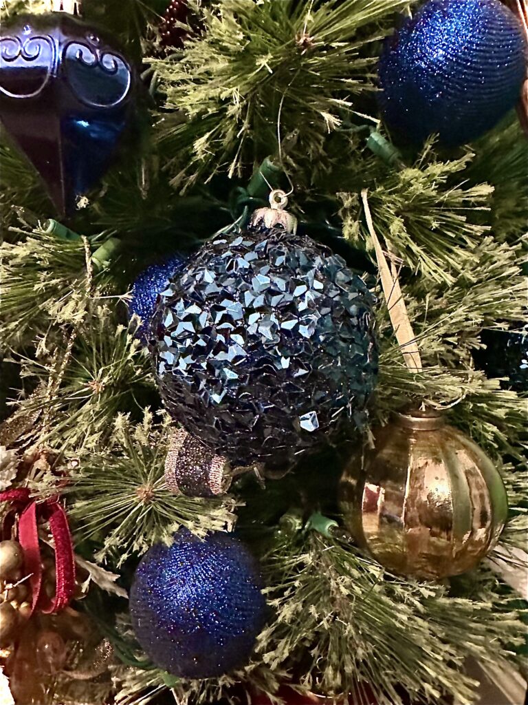 Deep blue Christmas ornaments paired with gold glitter picks on a festive Christmas tree