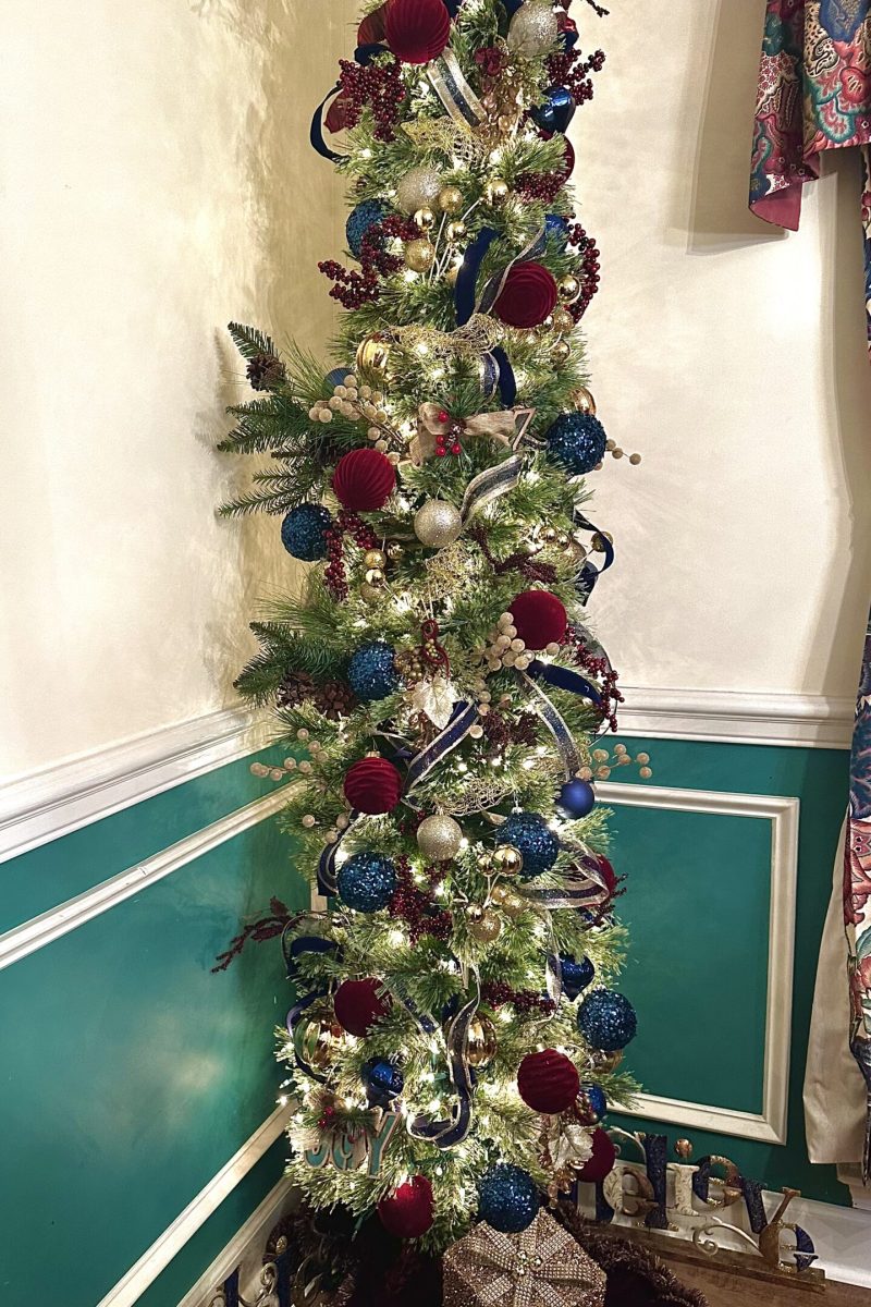 Dining room Christmas tree decorated with red velvet ornaments, deep blue ornaments, gold picks, and ribbon