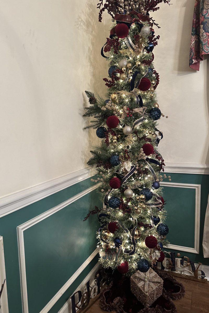 Dining room Christmas tree decorated with red velvet ornaments, deep blue ornaments, gold picks, and ribbon