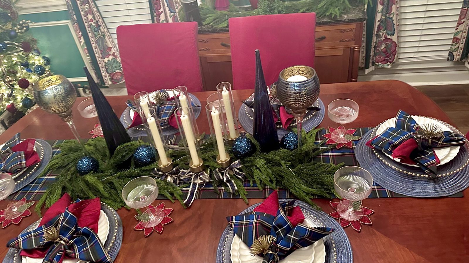 Dining room decorated for Christmas with blue and gold tablescape and velvet-accented Christmas tree. plaid blue green and gold table runner and napkins